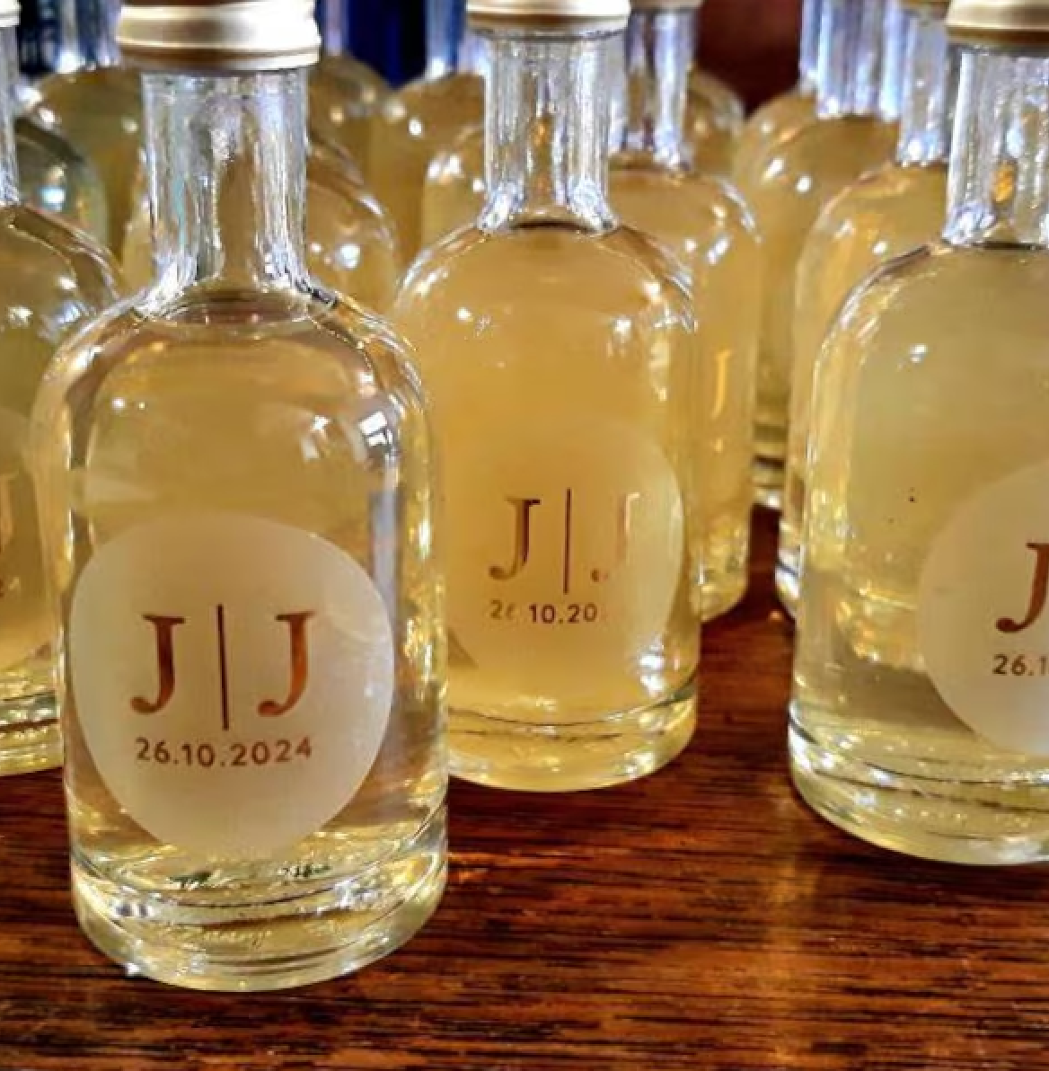 Customer's photo showing small alcoholic Shot favour bottles with personalised classic initials wedding stickers