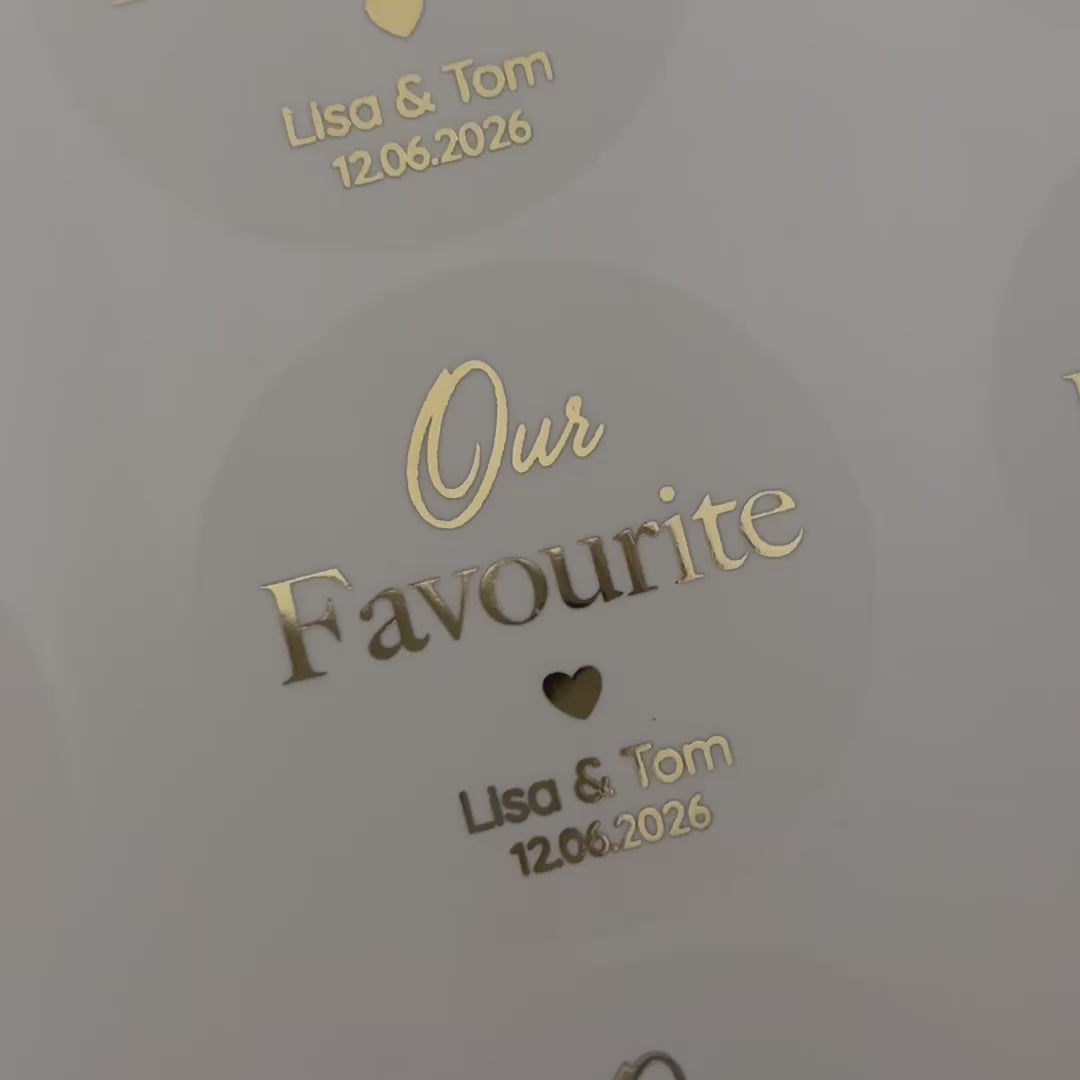 Load video: Personalised &#39;our favourite&#39; Wedding Stickers with names and date moving to show the high shine gold foil finish